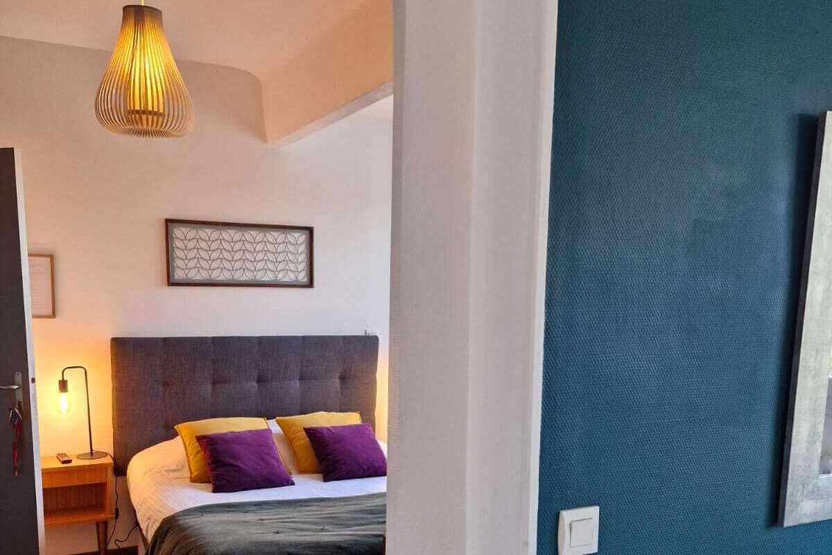 Un dormitorio con una cama, una mesita de noche, una lámpara y un cuadro colgado en la pared.