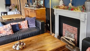 Un salon chaleureux avec un mur bleu foncé, une cheminée, une table basse en bois et un canapé confortable.