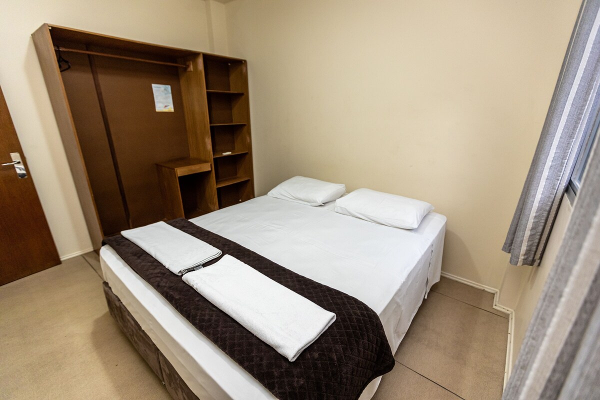 A bedroom with a bed, a wardrobe, and a bathroom.