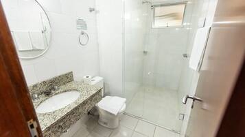 Uma casa de banho com lavatório de bancada em granito, sanita e cabine de duche com parede de vidro.