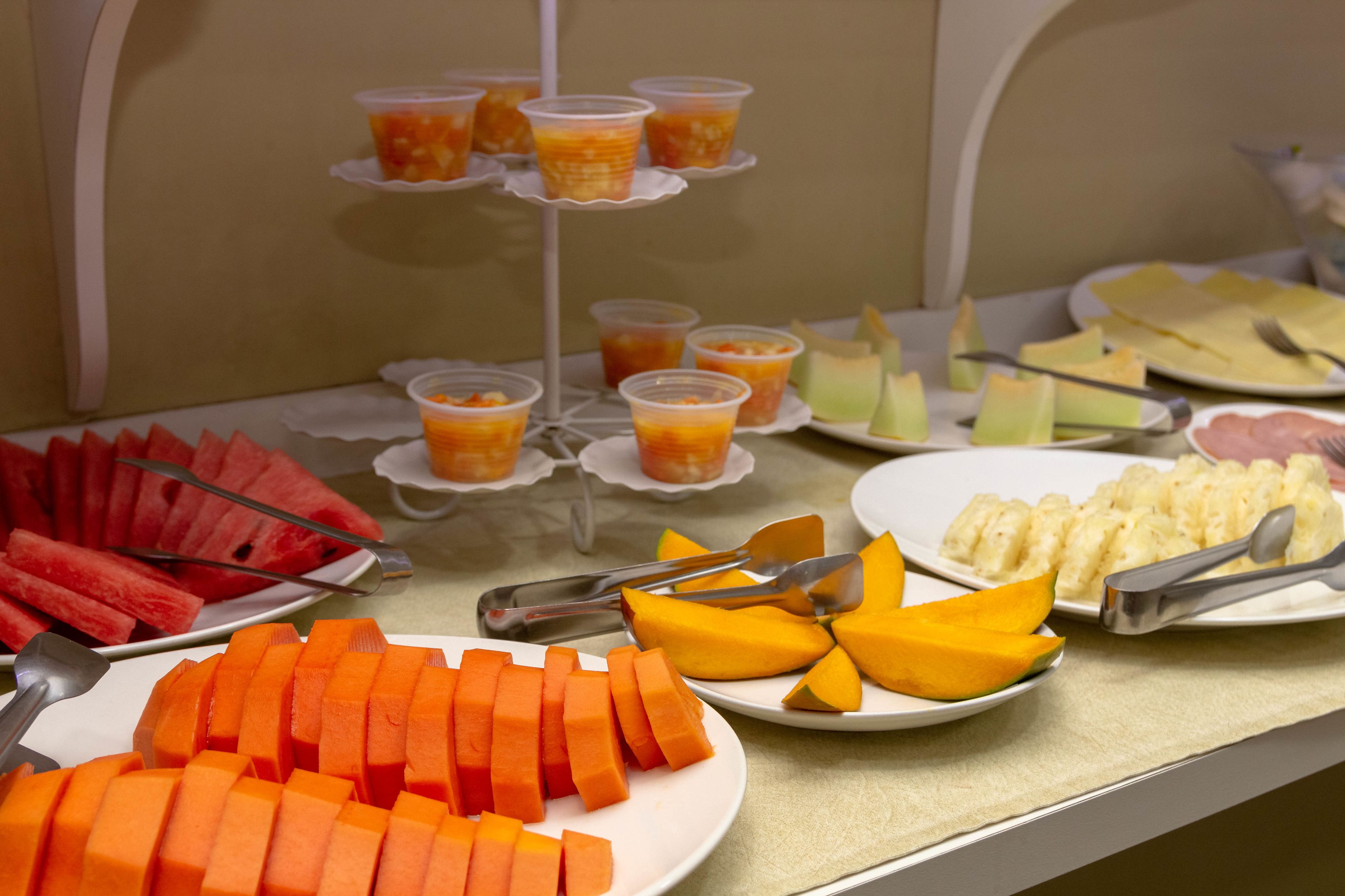A buffet with various fruits and vegetables, including watermelon, carrots, and mangoes.