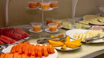 A buffet with various fruits and vegetables, including watermelon, carrots, and mangoes.