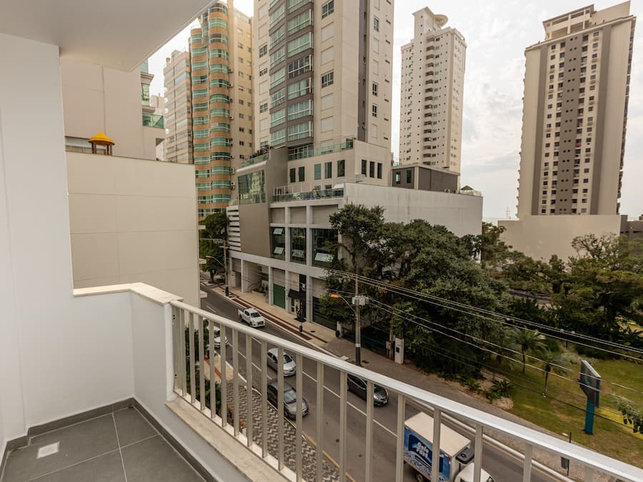 Un balcón con vistas a un paisaje urbano, incluyendo edificios altos y una calle con coches.