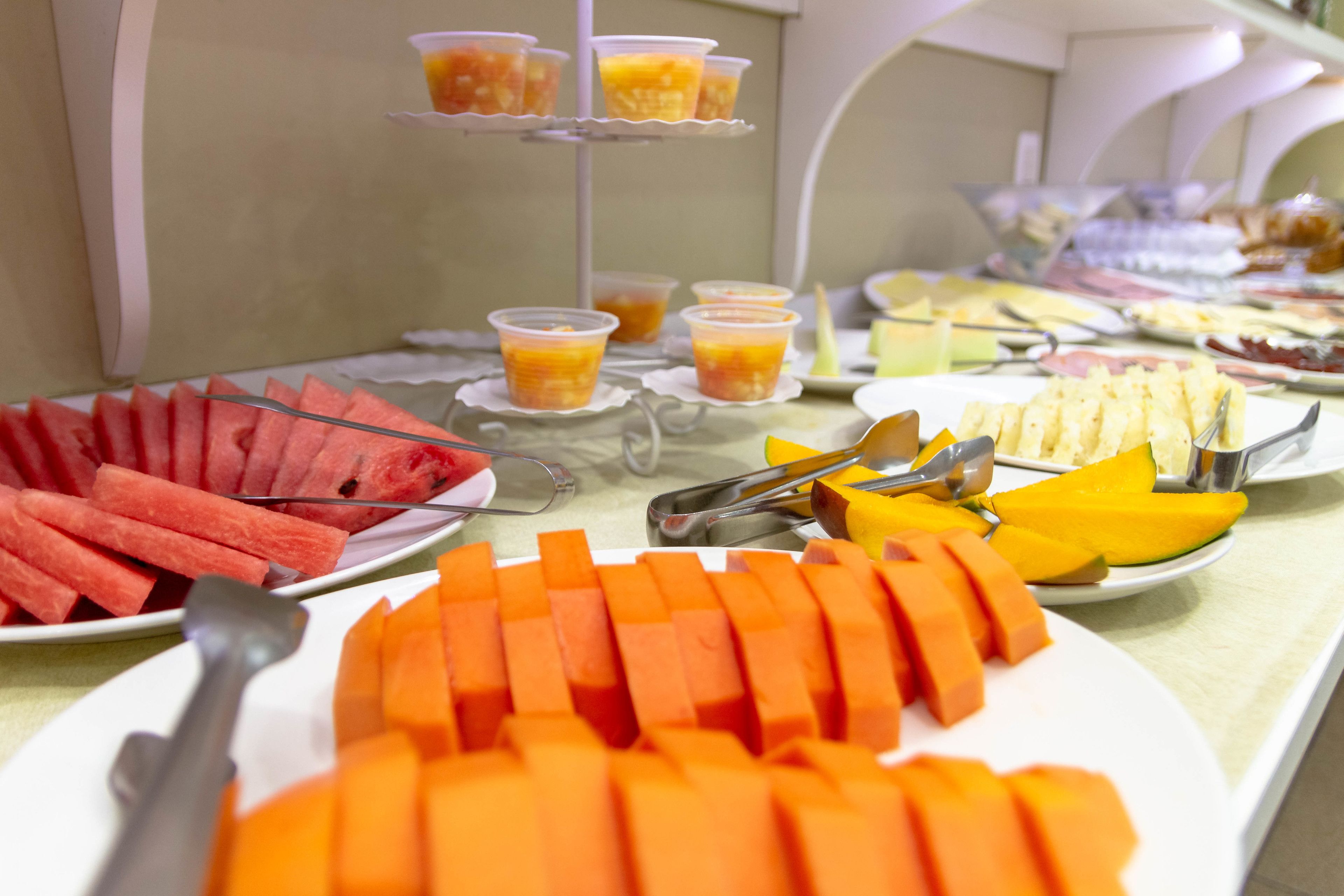 A buffet with various food items including watermelon, mango, and cheese.
