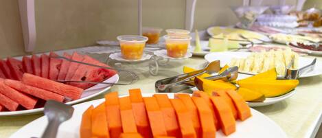 Un bufé con diversas opciones de comida, incluyendo sandía, mango y queso.
