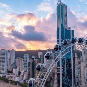 A cityscape with a prominent Ferris wheel and a tall building with 'FC' signage. - Hotel do Bosque (Balneário Camboriú)