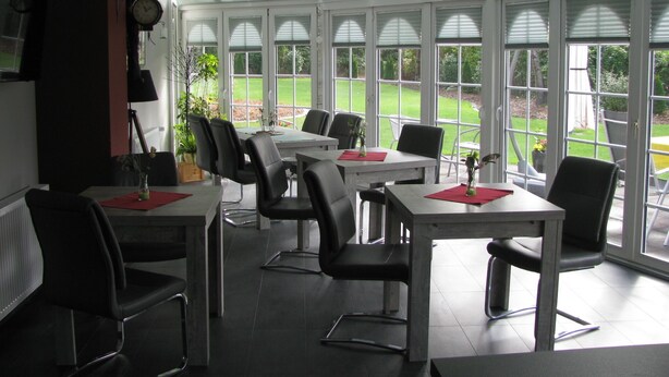 Un salón de conferencias con mesas y sillas, ventanas amplias y vistas al exterior.