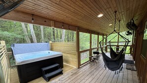 A wooden deck with a hot tub, a hammock, and a view of the forest. - Soul Sister- Creek View, WiFi, Firepit, WiFi, Hiking, 4 mins to Natural Bridge (Campton)