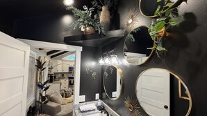 A modern bathroom with a dark wall, multiple mirrors, a sink, and a plant. - Soul Sister- Creek View, WiFi, Firepit, WiFi, Hiking, 4 mins to Natural Bridge (Campton)