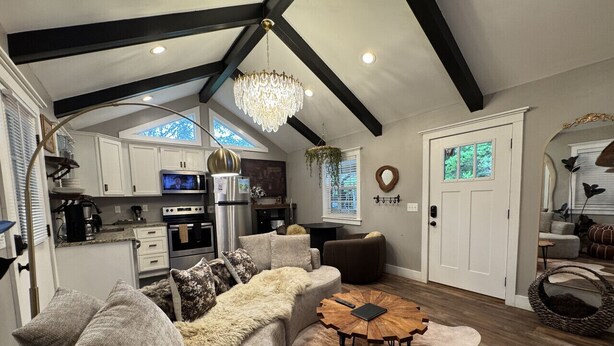 A spacious living area with a large sofa, a coffee table, and a chandelier. - Soul Sister- Creek View, WiFi, Firepit, WiFi, Hiking, 4 mins to Natural Bridge (Campton)