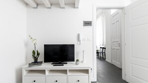 Un mobile TV bianco con un televisore a schermo piatto, una piccola pianta in vaso e un telecomando.