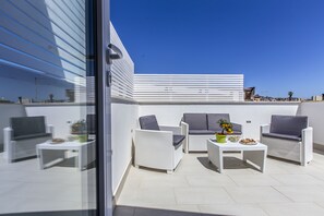 A modern outdoor patio with white wicker furniture, including sofas and armchairs, arranged around two small tables. - Aruci B&B (Syracuse)