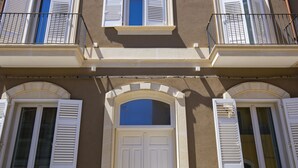 Un edificio con diverse finestre, alcune dotate di persiane, e balconi con ringhiere.
