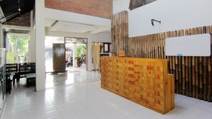 A reception area with a wooden reception desk, a bamboo wall, and a whiteboard. - Griya Jagadhaya (Sewon)
