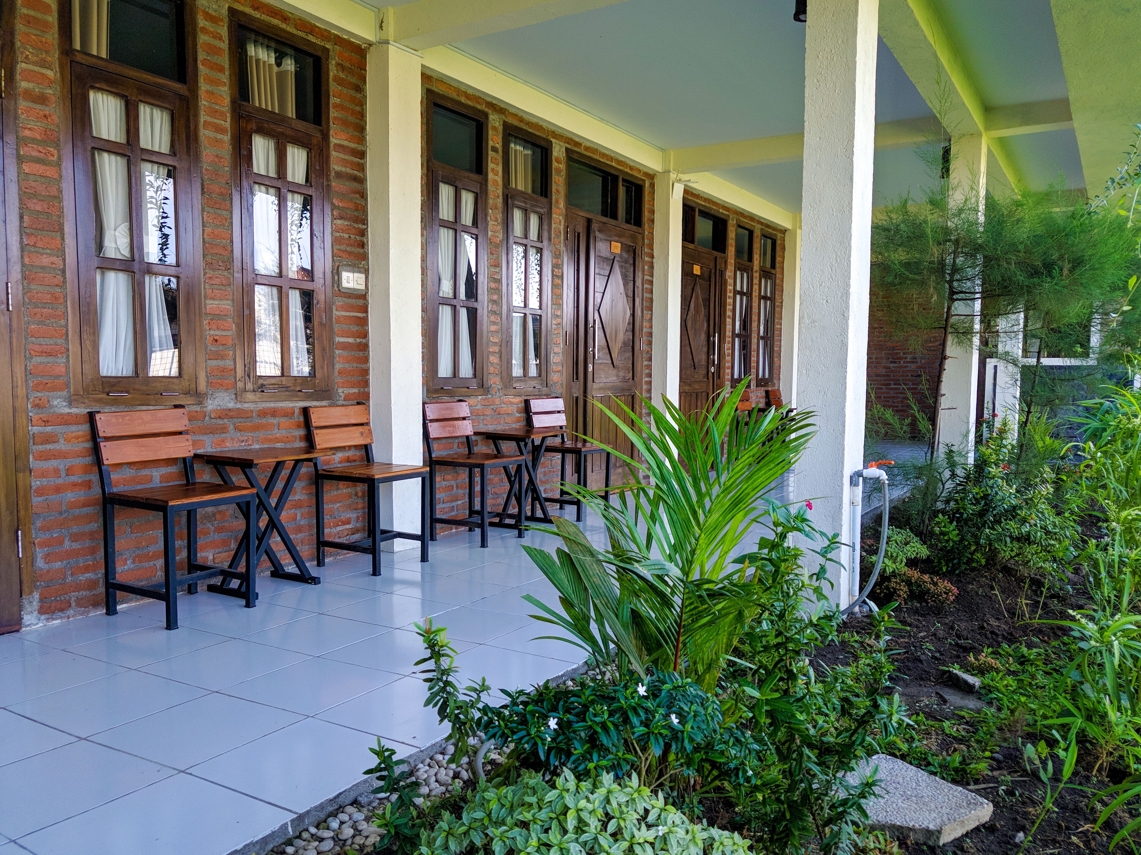 A covered outdoor seating area with brick walls and wooden benches.