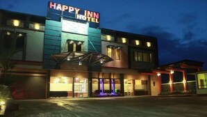 A hotel with a sign reading "HAPPY INN HOTEL" and a covered entrance area. - Happy Inn Hotel (Kendari)