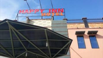 A building with a sign that reads "HAPPY INN HOTEL" and a modern glass structure in front.