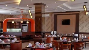 A modern restaurant with multiple dining areas, including a bar and a seating area with tables and chairs. - Happy Inn Hotel (Kendari)