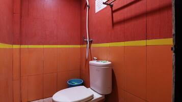 Un baño pequeño con paredes rojas, un inodoro blanco, un cubo de basura azul y un cabezal de ducha blanco.