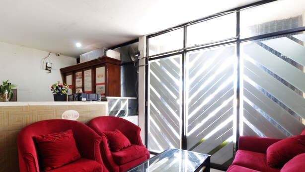 Una zona de recepción con mostrador, dos sofás rojos, una mesa de vidrio y vista a una escalera exterior.