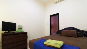 Un dormitorio con una cama, un televisor en una cómoda y una puerta.