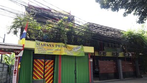 Un edificio con fachada verde, un letrero amarillo y un toldo a rayas rojas y amarillas.