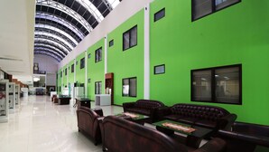A spacious lobby with green walls, leather sofas, and a high ceiling with skylights. - Wisma Konservasi (Jakarta)