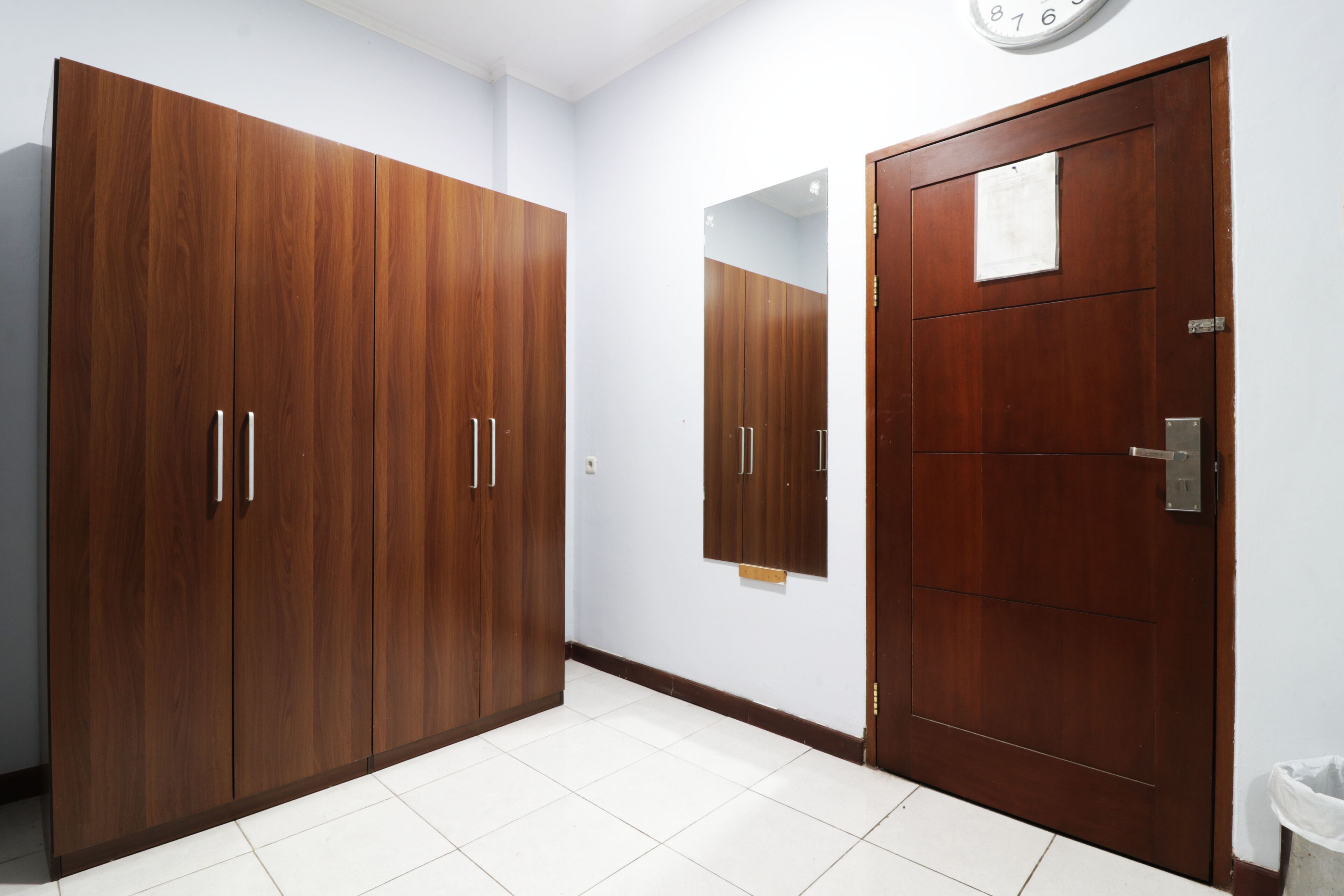 A room with a large wardrobe, a door, and a mirror.