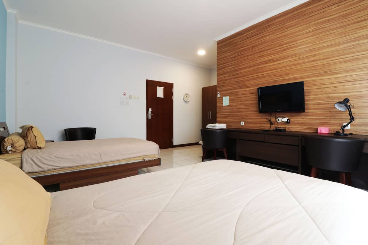 Habitación de hotel con dos camas, una pared de acento de madera, un televisor, un escritorio con silla y una lámpara.