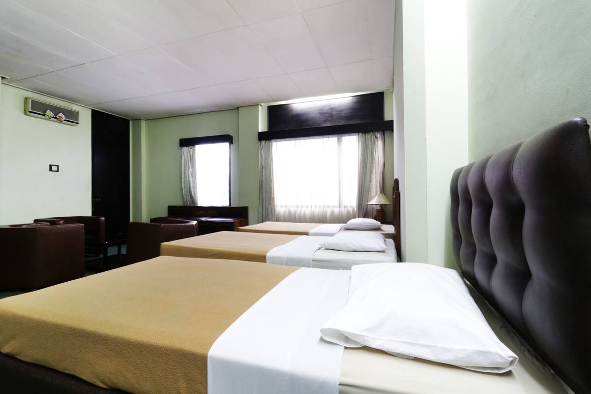Hotellihuone, jossa on kaksi sänkyä, työpöytä ja tuoli.
