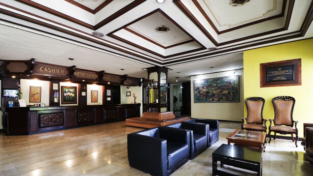 A lobby with a reception desk, seating area, and a painting on the wall. - Hotel Istana Bandung (Bandung)