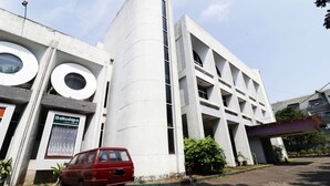 A modern building with a unique circular design, a red car parked in front, and a sign indicating a business or office space. - Hotel Istana Bandung (Bandung)