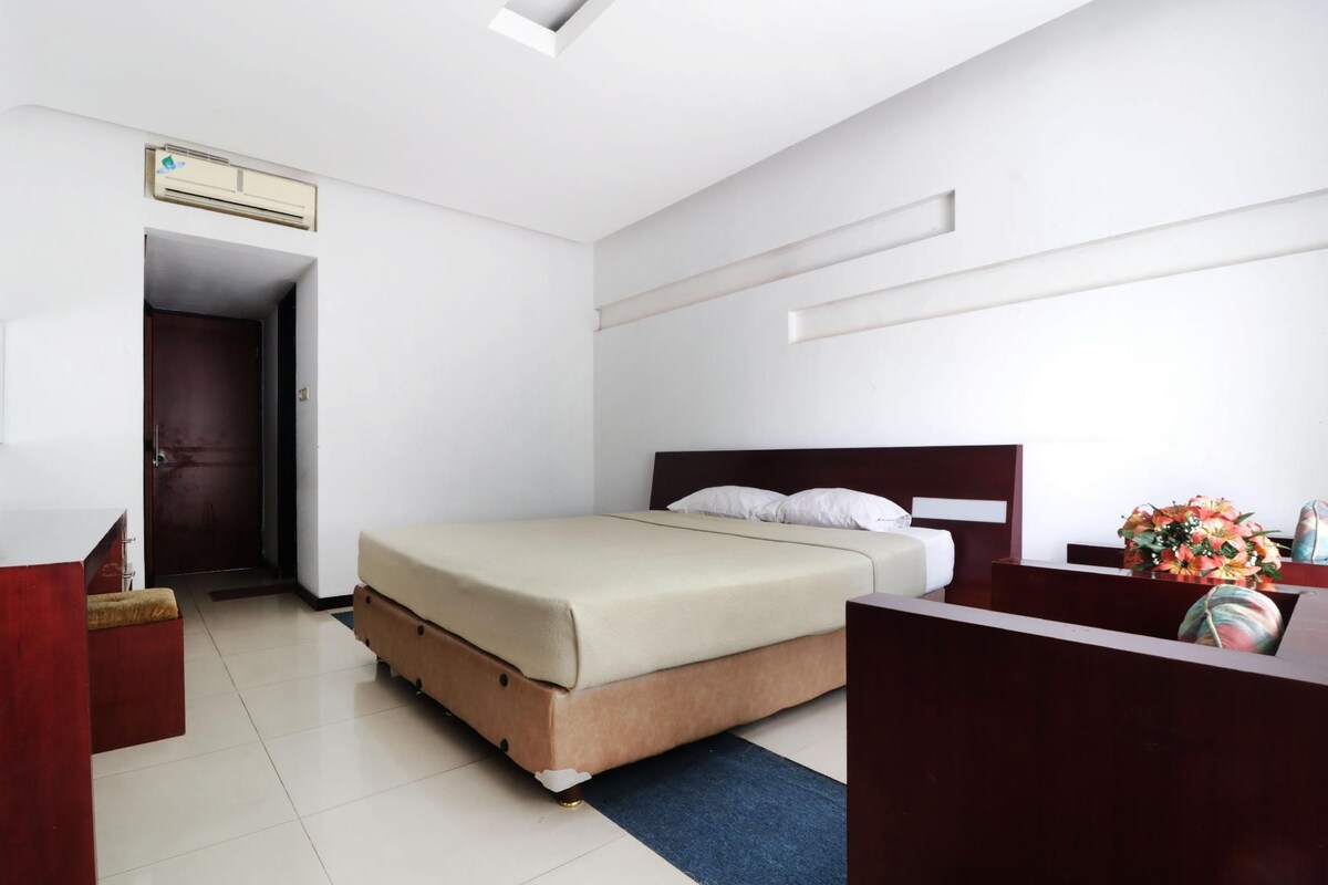 A modern hotel room with a bed, a desk, and a dresser.