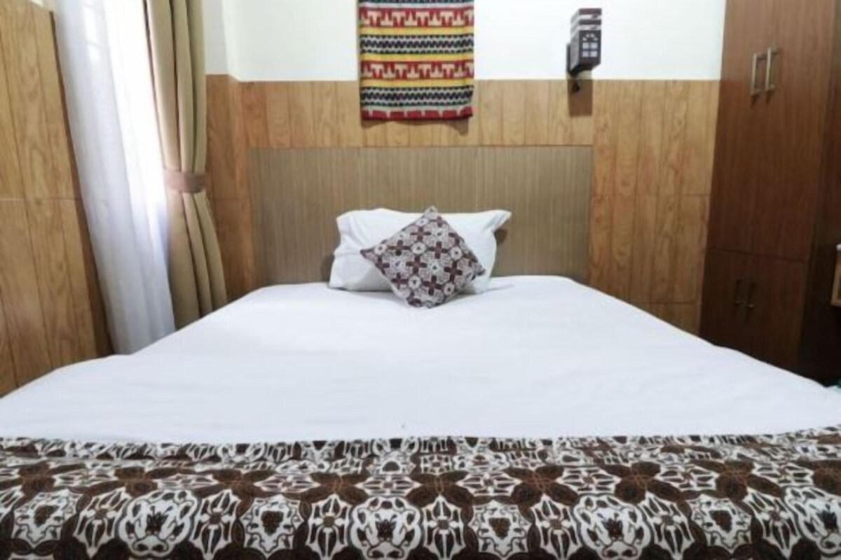 A bedroom with a wooden headboard, a patterned bedspread, and a decorative pillow.