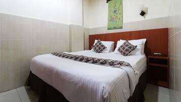 Ein Hotelzimmer mit einem großen Bett, einem hölzernen Kopfteil, einem Nachttisch und einem grünen Wandbild.