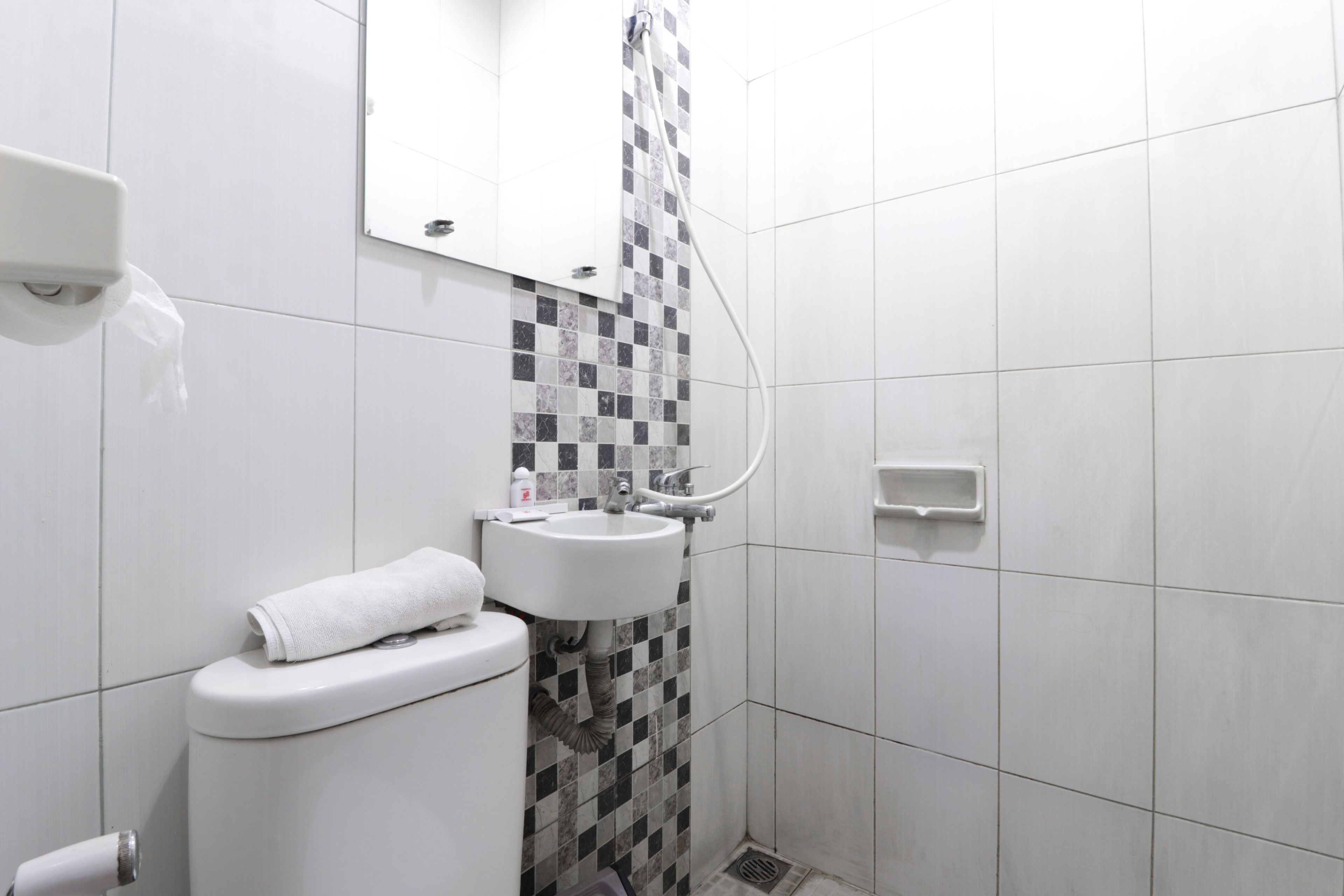 Et badeværelse med toilet, vask og brusebad.