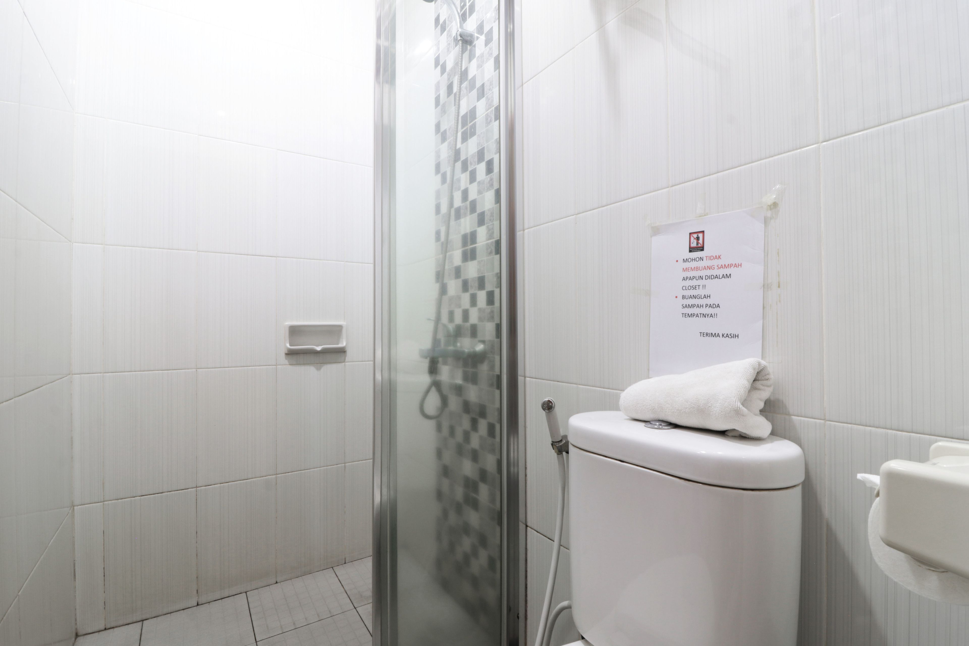 Une salle de bain avec une douche à parois de verre, des toilettes et un panneau avec du texte.