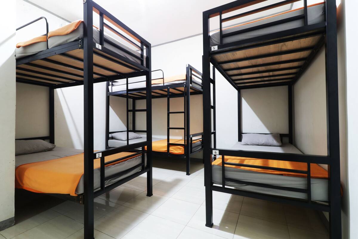 Bunk beds with orange bedding, white walls, and a tiled floor.