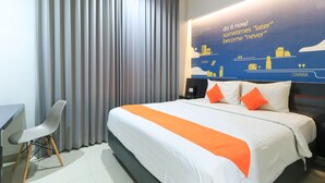 A hotel room with a bed, a desk, and a chair. - Hotel Berlian International (Surabaya)