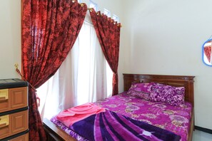A bedroom with a bed, curtains, a dresser, and a mirror. - Homestay Pelangi Batu (Batu)