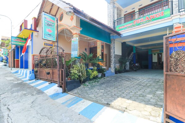 A hotel entrance with a tiled driveway, a blue and white striped pathway, and a signboard for 'Home Stay Pelangi'. - Homestay Pelangi Batu (Batu)