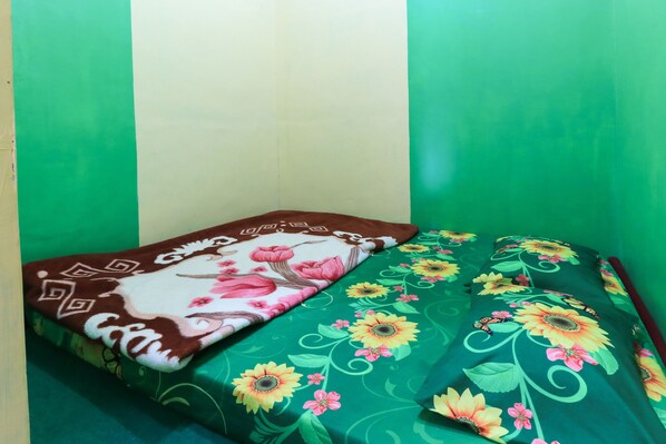 Una cama con ropa de cama floral frente a una pared verde.