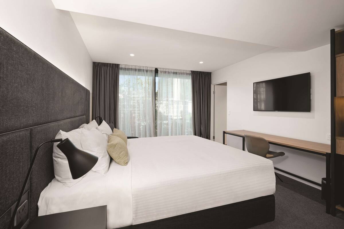 Ein modernes Hotelzimmer mit einem großen Bett, einem Schreibtisch und einem Flachbildfernseher.