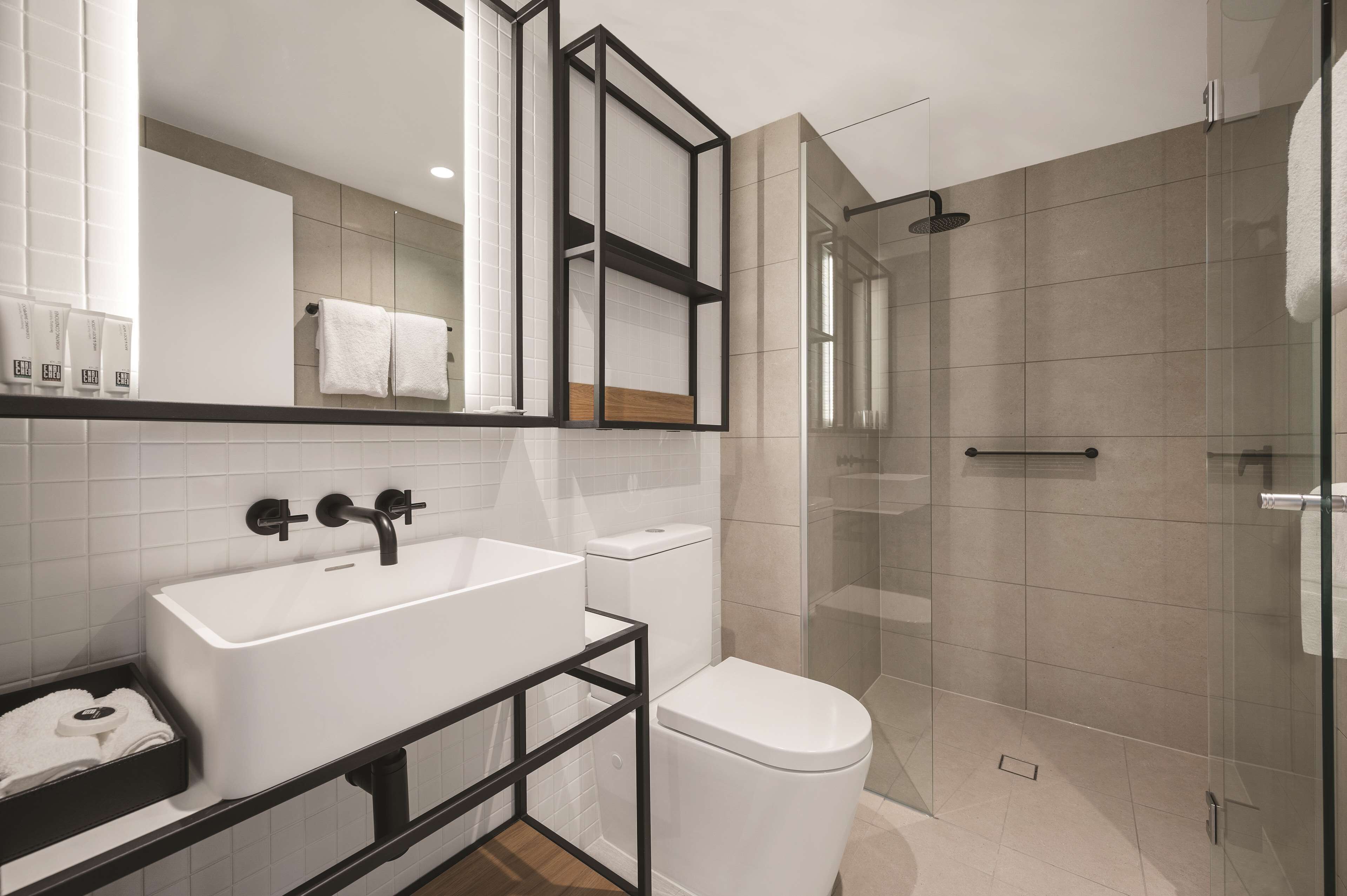 A modern bathroom with a white sink, a toilet, and a glass-enclosed shower.