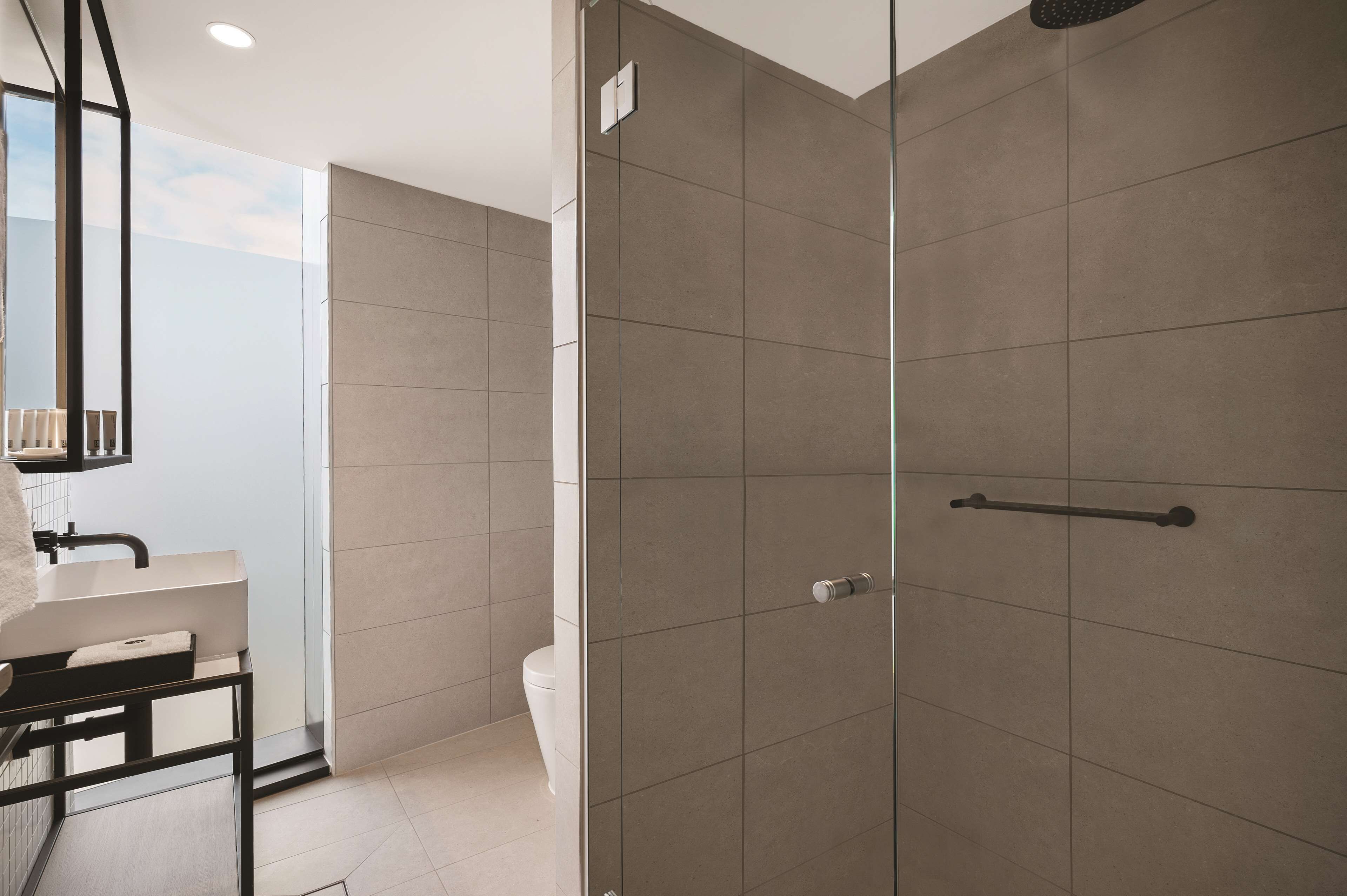 Une salle de bain moderne avec une douche à parois de verre, un lavabo blanc et un porte-serviettes.