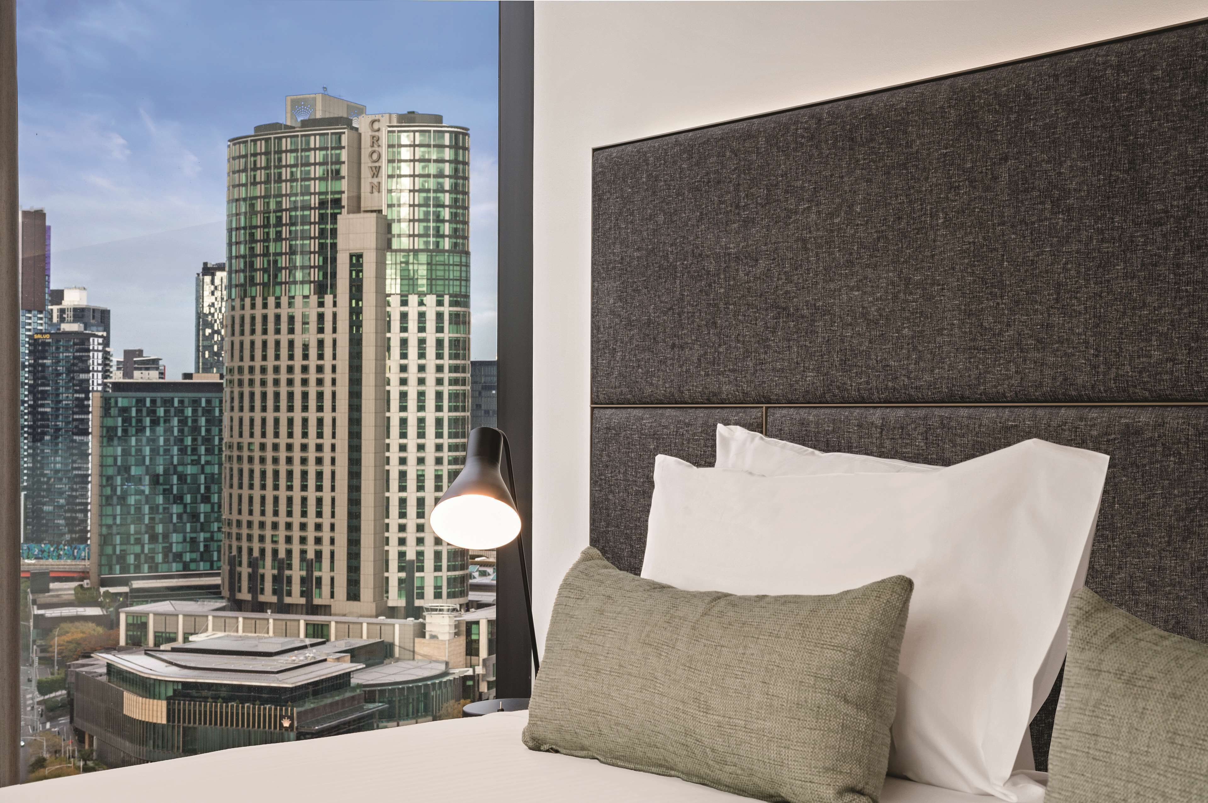 A hotel room with a city view, a modern bed, and a large window.