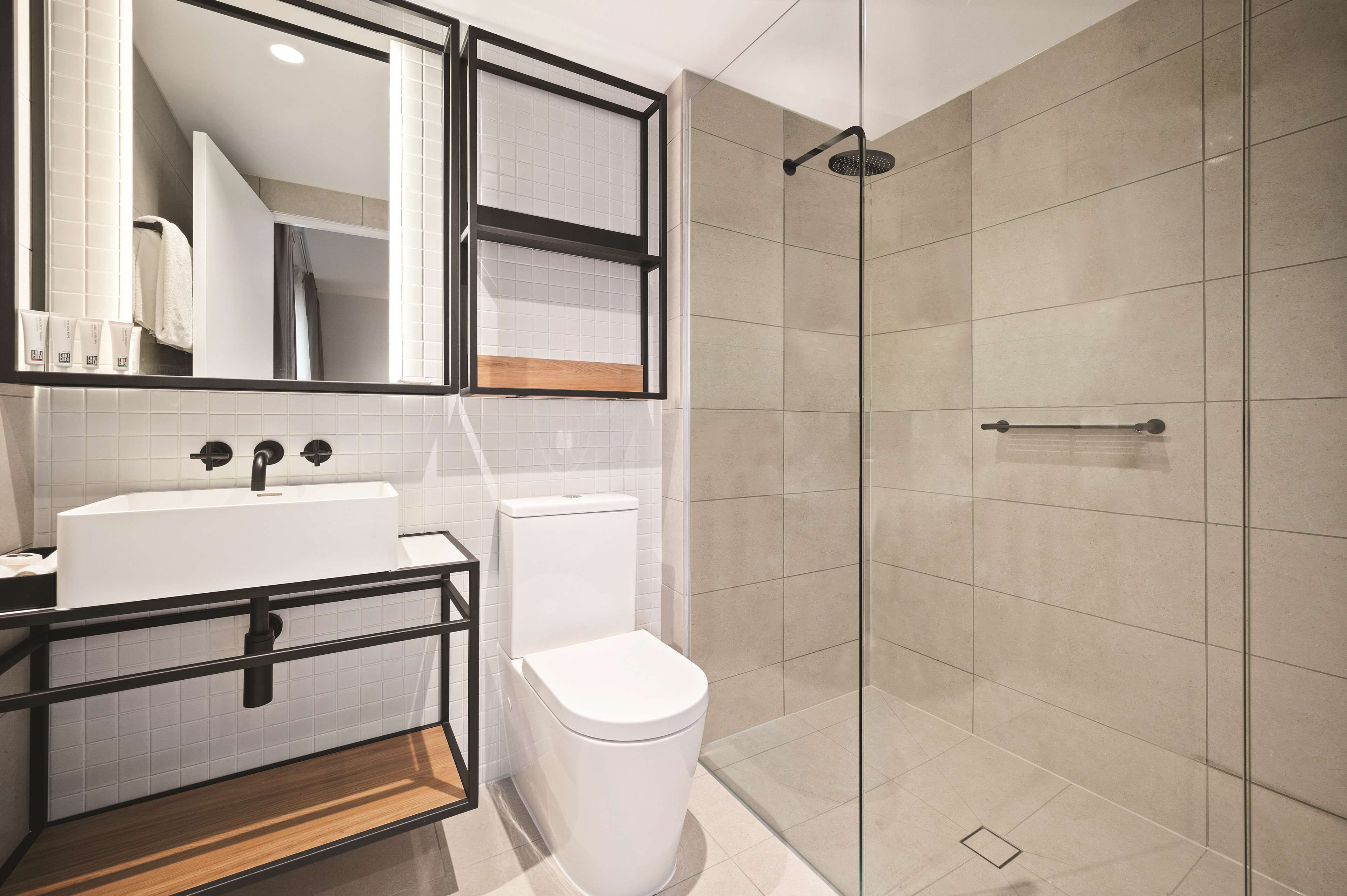 A modern bathroom with a white sink, toilet, and glass shower enclosure.