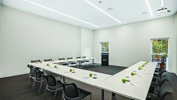 Una sala de conferencias con una mesa larga, sillas, un atril y un proyector.