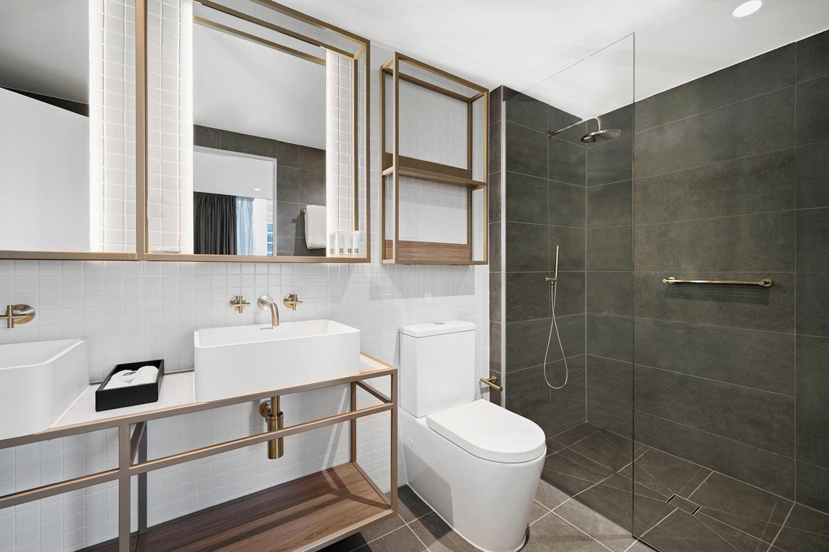 A modern bathroom with a vanity, a toilet, a shower enclosure, and a large mirror.