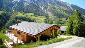 Une cabane en bois avec un toit en pente, un balcon et une vue sur une montagne.